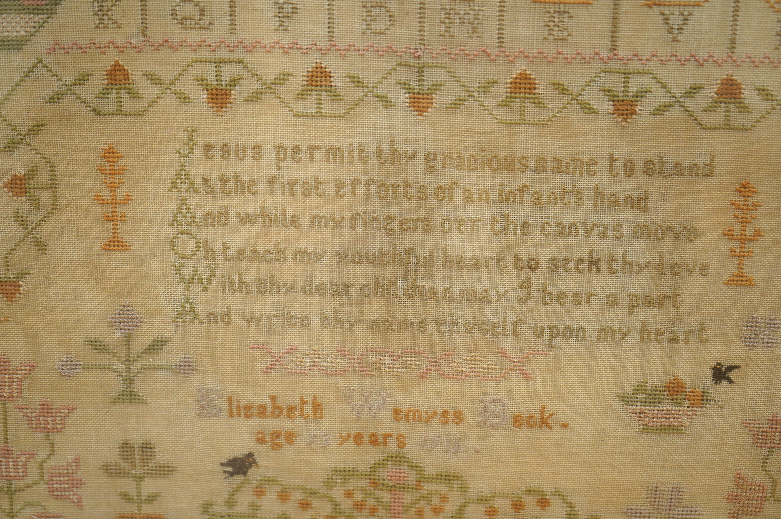 Two samplers; one late 18th century, the other early 20th century, the 18th century sampler by Elizabeth Chamberlain dated 1777, worked with an alphabet and framed verse bordered with vineous flowers, the later sampler b